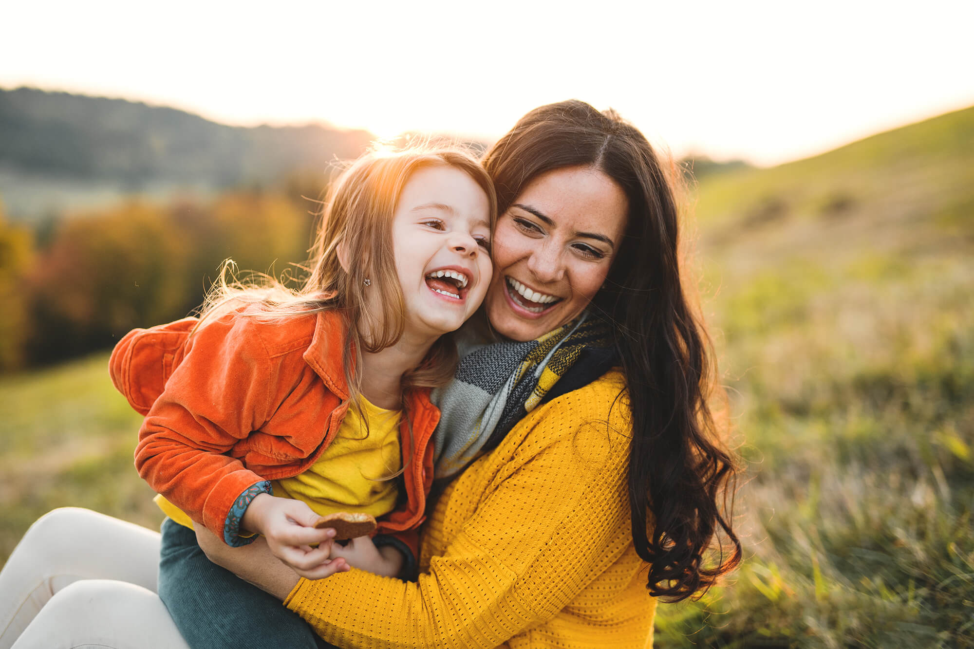 Young mother with a small daughter in autumn nature at sunset